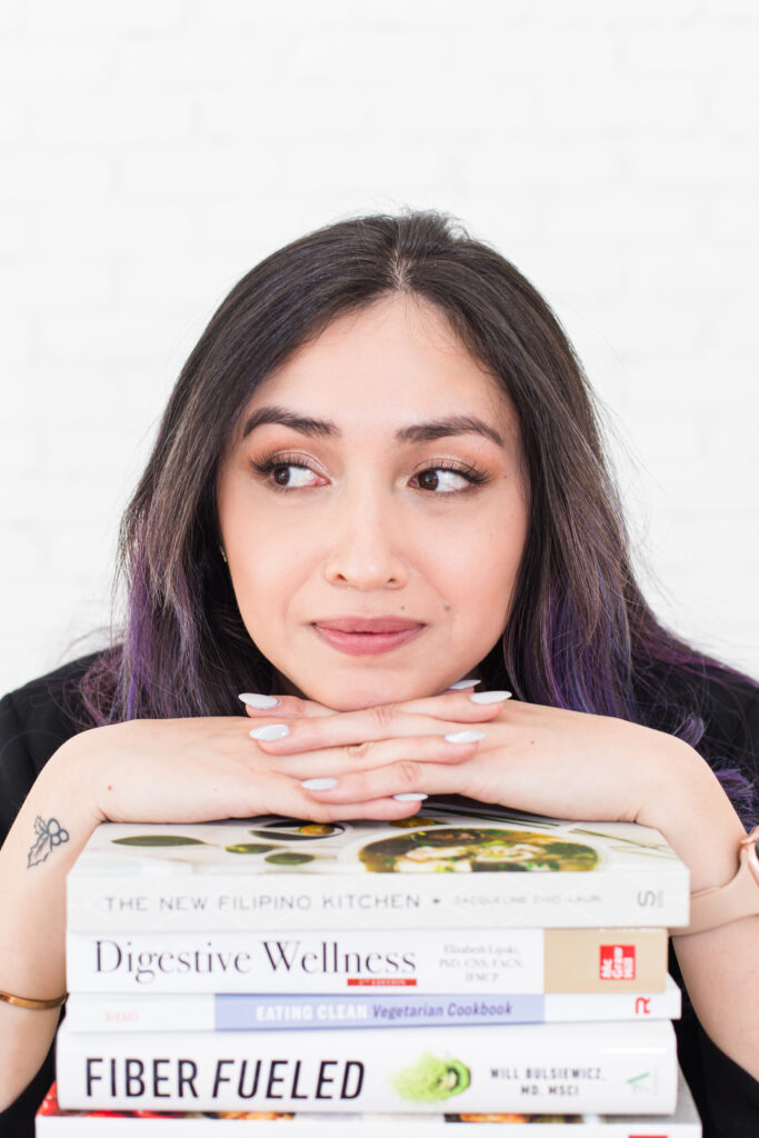 Woman leaning on a stack of books about digestion and wellness